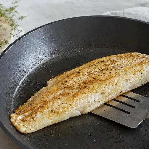 Hele witvisfilet die goudbruin in de pan wordt gebakken
