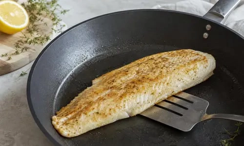 Hele witvisfilet die goudbruin in een koekenpan wordt gebakken